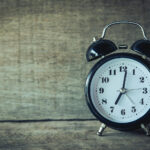 Alarm clock on a wooden surface, symbolizing the importance of timely financial planning and life insurance decisions.